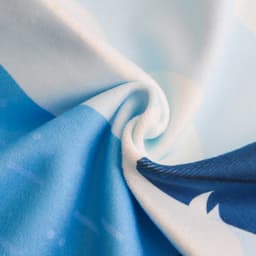 A microfibre beach towel in shades of blue, featuring a soft texture and vibrant patterns. It has a logo.