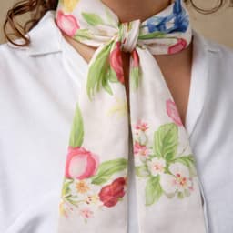 A floral-patterned long scarf in soft hues of pink, green, and blue, tied around a person's neck.