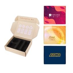 A subscription box packaging in beige with black inserts, accompanied by three colourful printed cards.