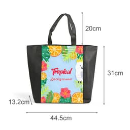 A tote bag with a full-colour tropical design featuring fruits, flowers, and a parrot, plus a black base and handles.