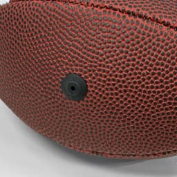 A mini promotional American football in red with a textured surface and a black valve.