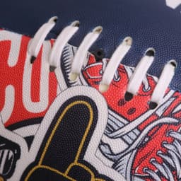 A training AFL ball in navy blue with red and white graphics, featuring stitching and a logo. 