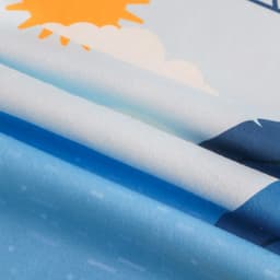 A microfibre beach towel in blue, featuring a sunny and cloud design with soft texture and vibrant colours.