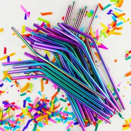 A group of multicoloured stainless steel straws with a shiny finish, surrounded by colourful confetti.