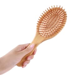 A bamboo airbag hair brush featuring a wooden handle and soft bristles, held in a hand.