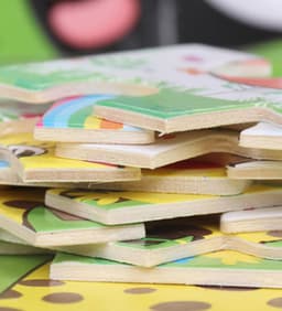 A stack of colourful wooden jigsaw puzzle pieces featuring various designs and characters.