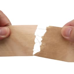 A person holds two pieces of water-activated reinforced kraft paper tape, displaying its brown colour and textured surface.