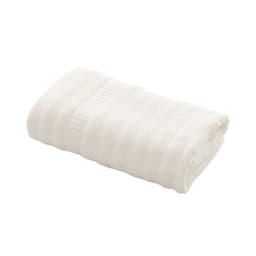 A cream-coloured bamboo fiber towel neatly folded, featuring a textured pattern. It includes a branded tag.
