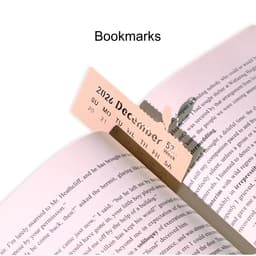 A pink bookmark positioned in a book, with a calendar date visible and a subtle logo in the corner.
