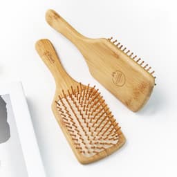 Two bamboo hair brushes with wooden bristles, featuring sleek, natural finishes and a minimalist design.