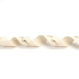 A wavy, cream cotton ribbon with hot stamping in gold. It features a decorative design and includes a logo.
