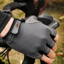 Anti-slip bike gloves in grey, featuring a textured surface and an adjustable strap, shown on a cyclist's hand.