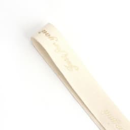 A pale cream cotton ribbon with gold hot stamping and a logo at one end.