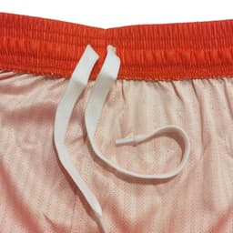 Breathable sport shorts in peach with an orange waistband and white drawstrings. Features a logo.