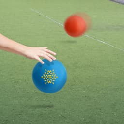 A blue inflatable PVC ball with a logo in a grassy outdoor setting, alongside a red ball in motion.