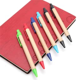 Kraft paper pens in green, red, blue, black, and turquoise arranged on a red notebook with a logo.
