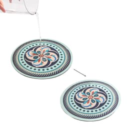 A round soft diatomaceous coaster in pastel colours with a floral pattern, featuring a hand pouring water onto its surface.