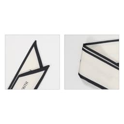 A narrow scarf in cream with black twill weave detailing and a logo. Showcases two angles of the product.