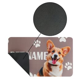 A pet feeding mat in brown featuring a smiling dog design and paw prints, with a textured black backing.