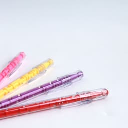 A set of colourful pens in pink, yellow, purple, and red, each featuring a maze design on the barrel.