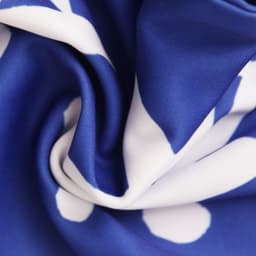 A knitted polyester scarf with a blue background and white polka dot pattern, featuring a soft, textured fabric.