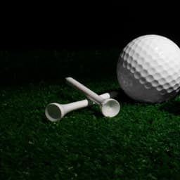 A bamboo golf tee in white, positioned next to a golf ball on green grass.