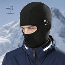 A black winter balaclava cycling face mask with an integrated windproof feature, worn by a person against a mountainous background.