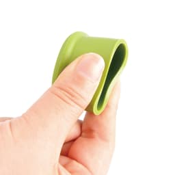 A drink bottle top with a green silicone wine stopper being held by a hand, showcasing its flexible design.