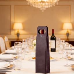 A drink bottle bag in dark burgundy with a handle, set against an elegant dining table.