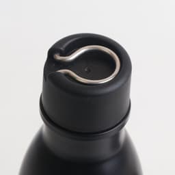 A drink bottle with a black stainless steel body and a metallic loop on the cap for easy handling.
