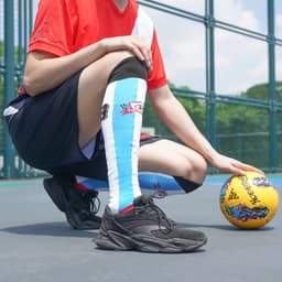 Knee high football socks in blue with black and red accents, featuring a towel bottom, paired with a red sports top.