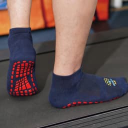 Crew Gripper Socks in navy blue with red grip patterns on the soles, displayed on a treadmill.