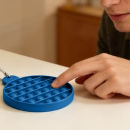 A blue Round Pop Bubble Board with multiple bubbles, being touched by a person's finger. It features a keychain attachment.
