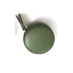 A green PU mini tape measure enclosed in a circular case with a loop for attachment.