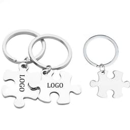 Stainless steel keychains shaped like puzzle pieces, featuring a logo, in silver colour.