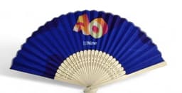 A bamboo and fabric folding fan in blue with a decorative design and a logo on the handle.