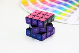 A Rubik's Cube 3x3 in black, purple, and blue featuring designs on the squares, alongside a colour palette guide.