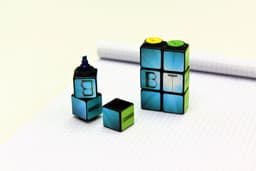 A set of four highlighters in black, blue, green, and yellow, designed in a Rubik's cube style, with a logo.