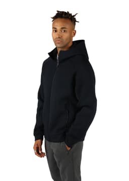 A black men's hoodie with a zip front, side pockets, and an attached hood, worn by a model.