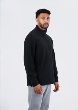A black men's/unisex polar fleece half zip top is displayed on a model against a plain background.