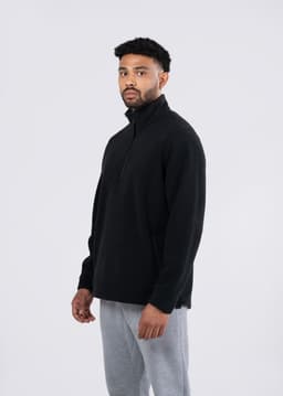 A black polar fleece half zip top for men and unisex, featuring a stand-up collar and a side logo.