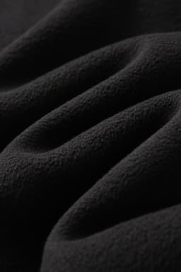 A soft black polar fleece fabric, featuring a textured surface with gentle folds and drapes.