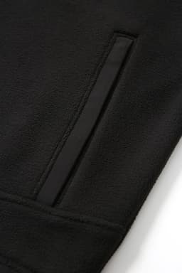 A close-up of a black polar fleece half zip top featuring a side pocket and a smooth fabric finish.