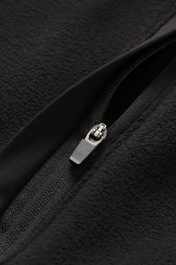 A close-up of a black polar fleece half zip top featuring a silver zipper detail and a soft texture.