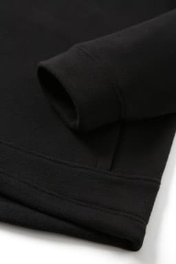 A black polar fleece half zip top featuring a folded sleeve and soft texture. It has a logo on the fabric.