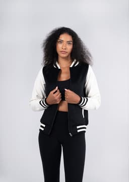 A black and white women's varsity jacket made from a soft wool blend, featuring a logo and striped detailing.