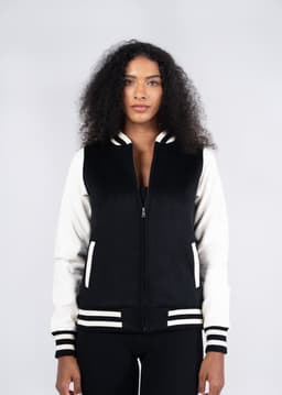 A black and white women's varsity jacket with a zip front, striped cuffs, and a logo on the chest.