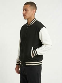A men's unisex wool blend varsity jacket in black with white sleeves and striped cuffs, featuring a logo on the chest.