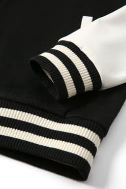 A black and white wool blend varsity jacket featuring ribbed cuffs with monochrome stripes. Includes a logo.