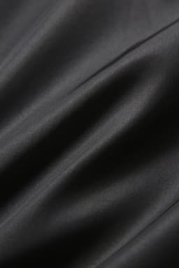 A close-up of smooth, black fabric showcasing soft texture and subtle sheen. The material appears fine and luxurious.